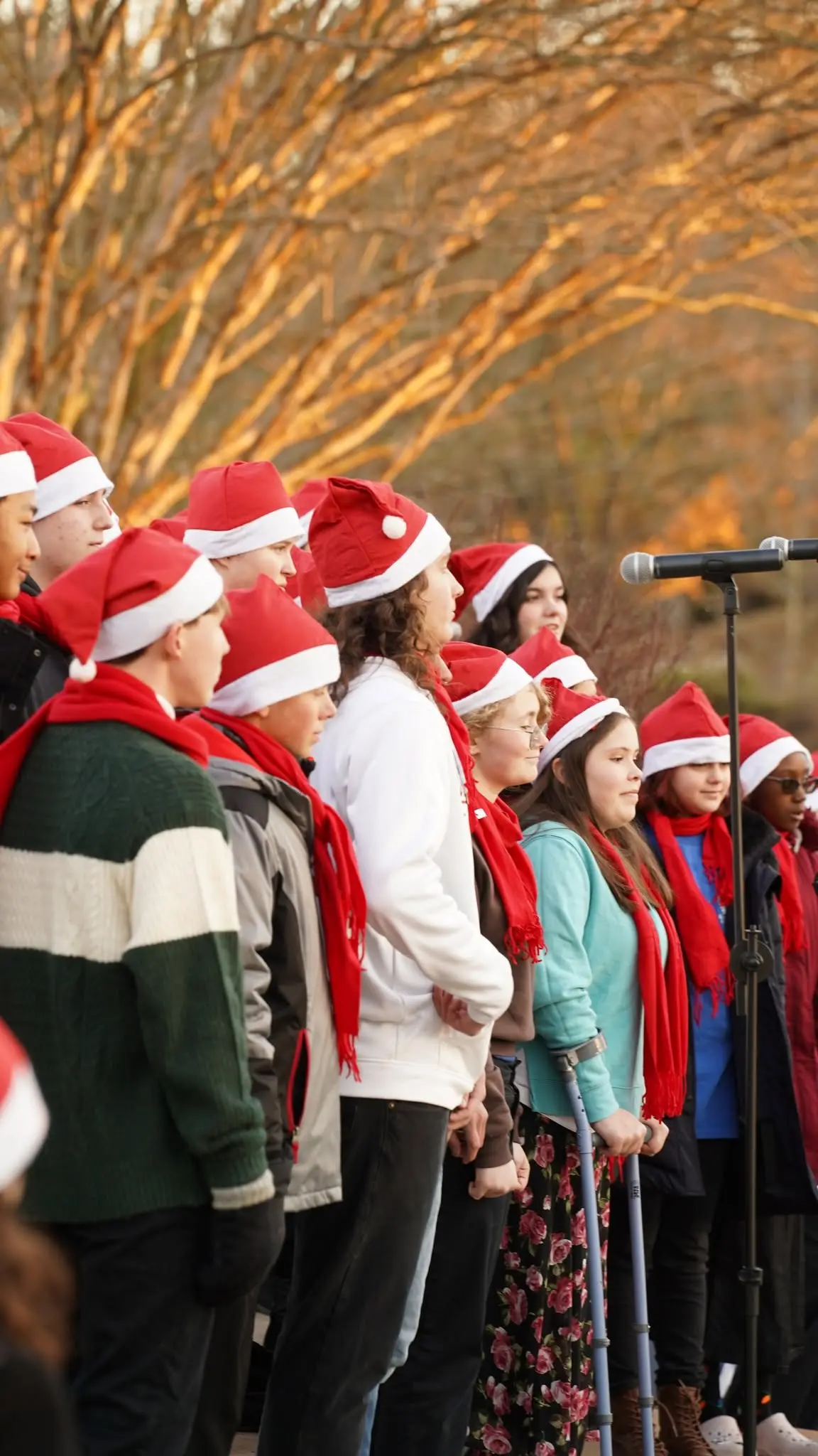 Choir members singing outdoors at a holiday event