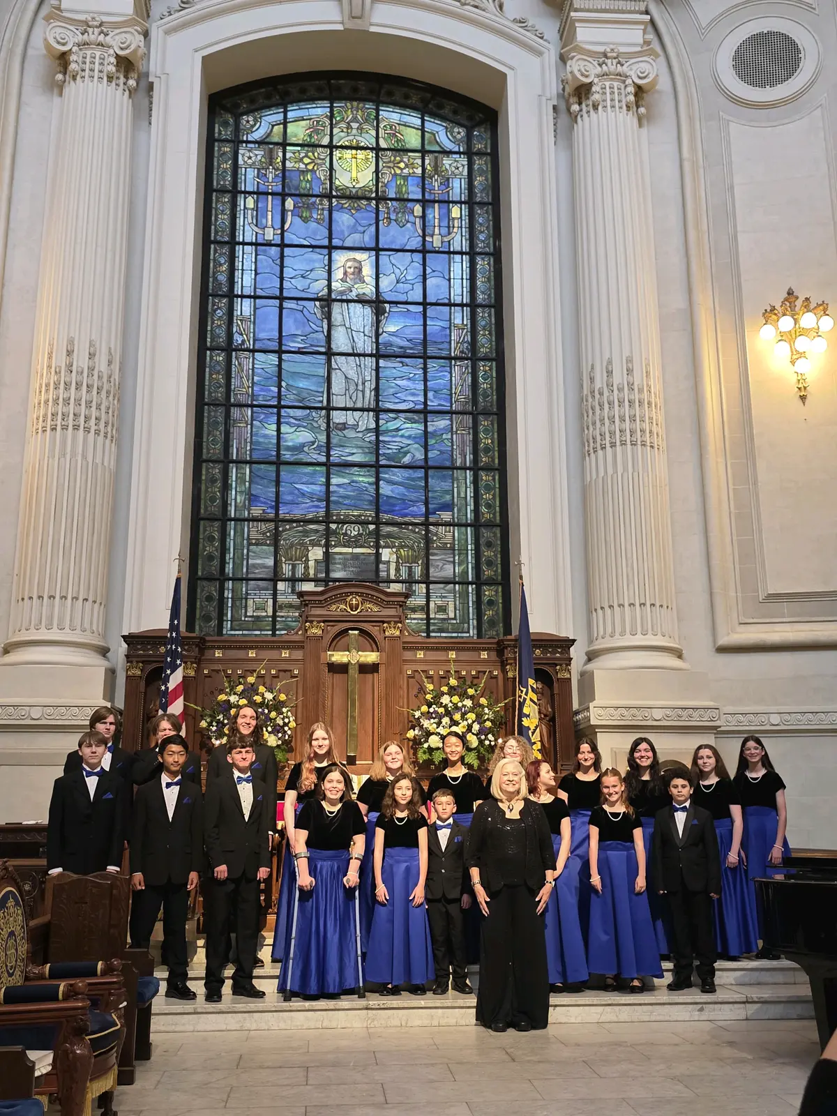 The choir performing beneath the stained glass window of the Naval Academy Chapel