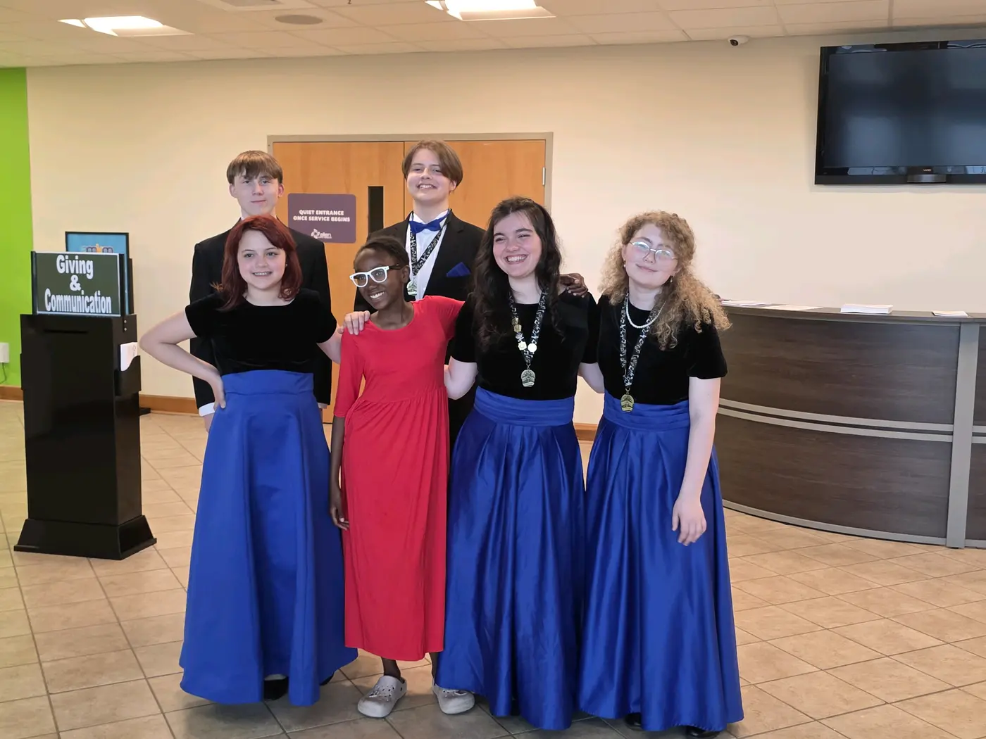 Five choir members in blue and black concert dress before a performance